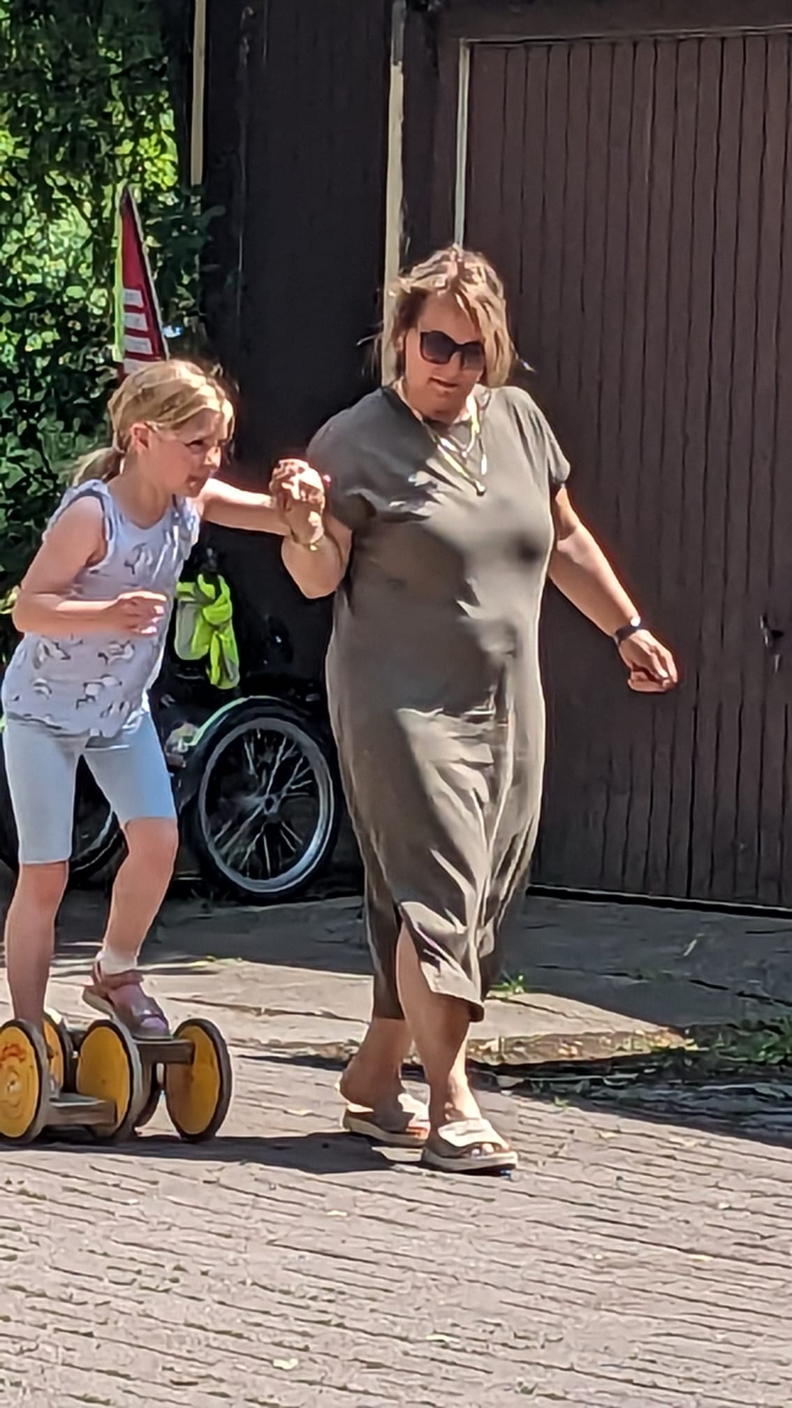 Eine Frau hilft einem Kind, auf einem Holzroller das Gleichgewicht zu halten